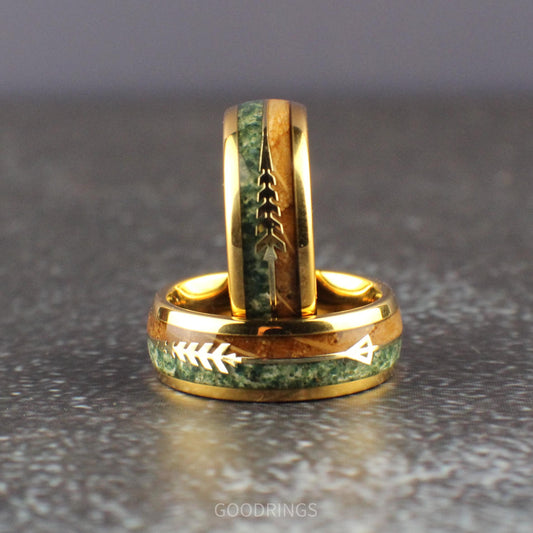 Domed gold ring with inlays of moss agate and burnt whiskey wood, separated by a gold arrow; unique design for a wedding or statement ring.